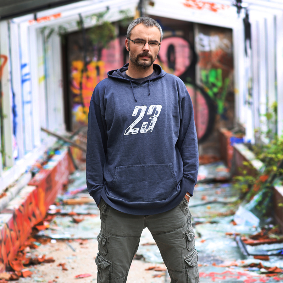 Der DJ Hatikwa steht vor einem buntem Tor.