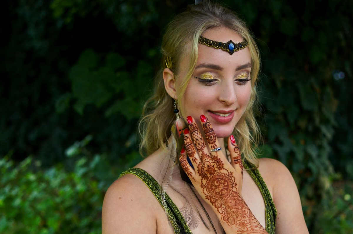 Linda May Linda May hat ihre mit Henna bemalte Hand an ihrem Hals liegen