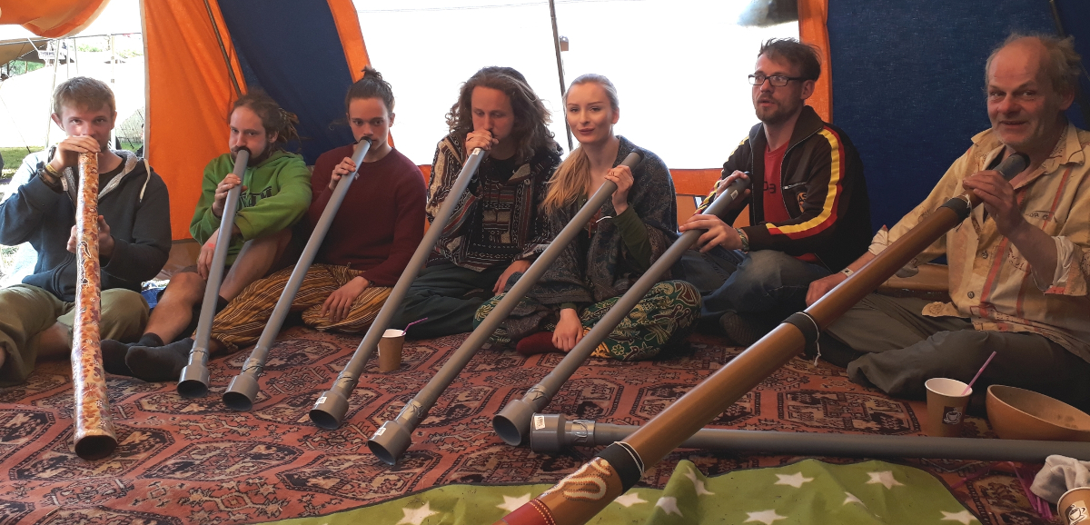 Didgeridoo Workshop 7 Menschen sitzen nebeneinander und spielen auf ihren Didgeridoos.