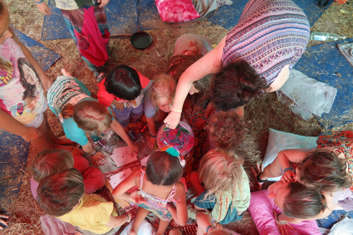 Hanna Salzer Hanna Salzer sitzt mit einer Gruppe von Kindern auf dem Boden und es wird gemeinsam gebastelt. Das Foto ist aus der Vogelperspektive aufgenommen.