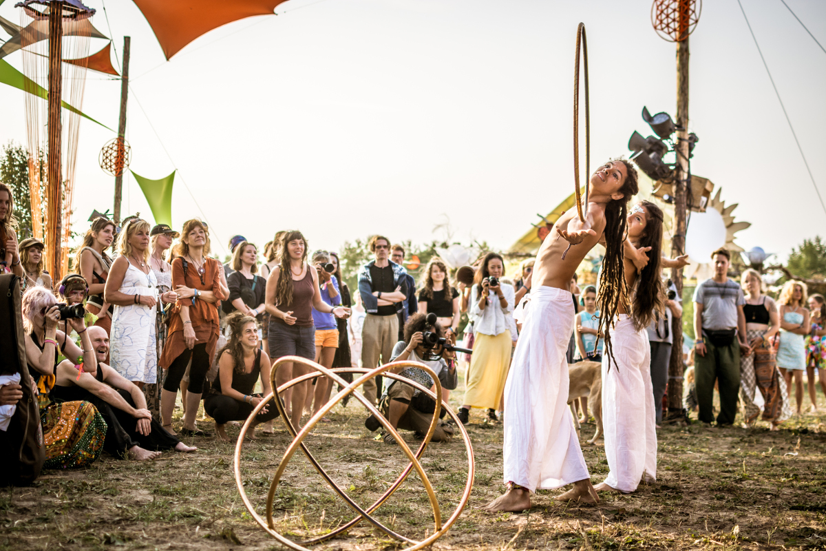 Vor einer Gruppe Menschen zeigen ein Mann und eine Frau in weißer Kleidung ihre Hula-Hoop Performance
