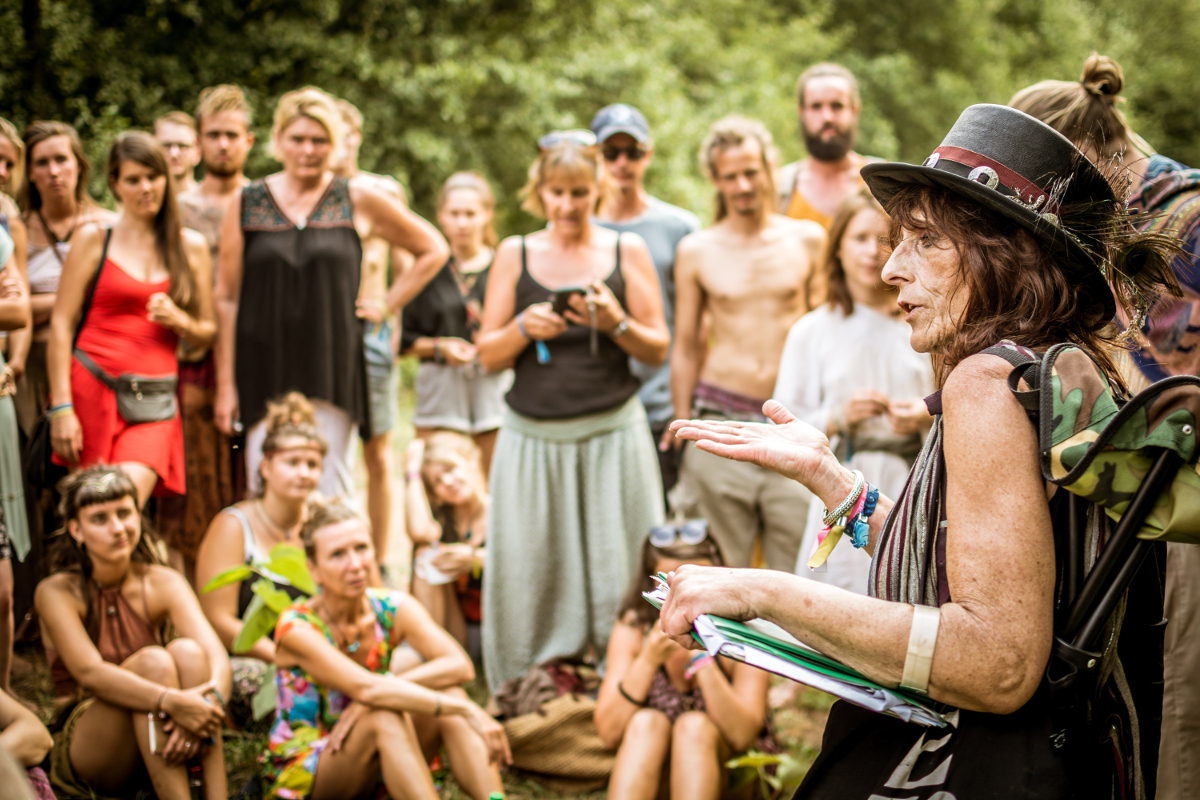 sibylle-mandragora-gruppe Sybill Mandragora steht am rechten Rand und spricht zu einer Gruppe Menschen.